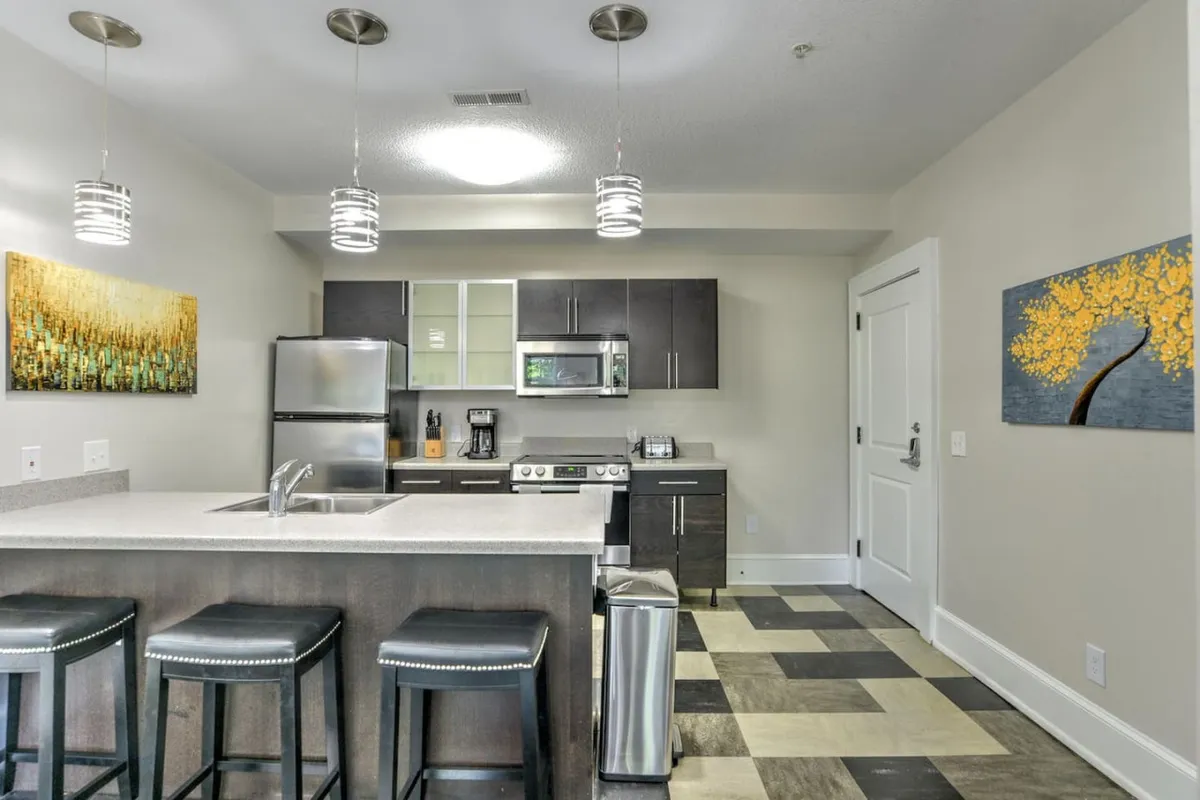 Another angle of the kitchen showing a large island, stainless steel appliances, and wall art, with a slightly different perspective that emphasizes the open, welcoming design. The setting is ideal for casual breakfasts, intimate dinners, or socializing around the kitchen.